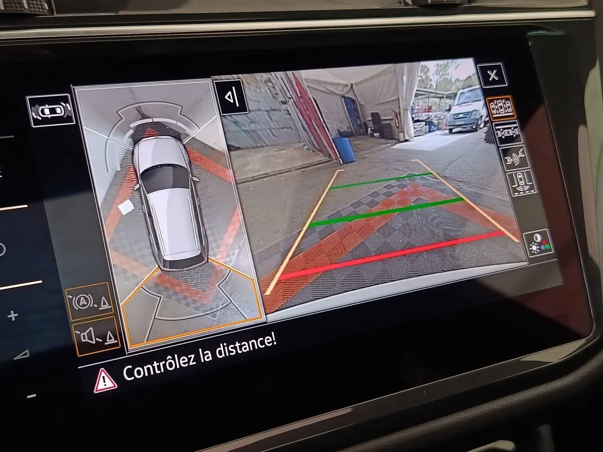 Écran tactile intérieur montrant la caméra 360° et vue arrière du Volkswagen Tiguan blanc en stationnement.