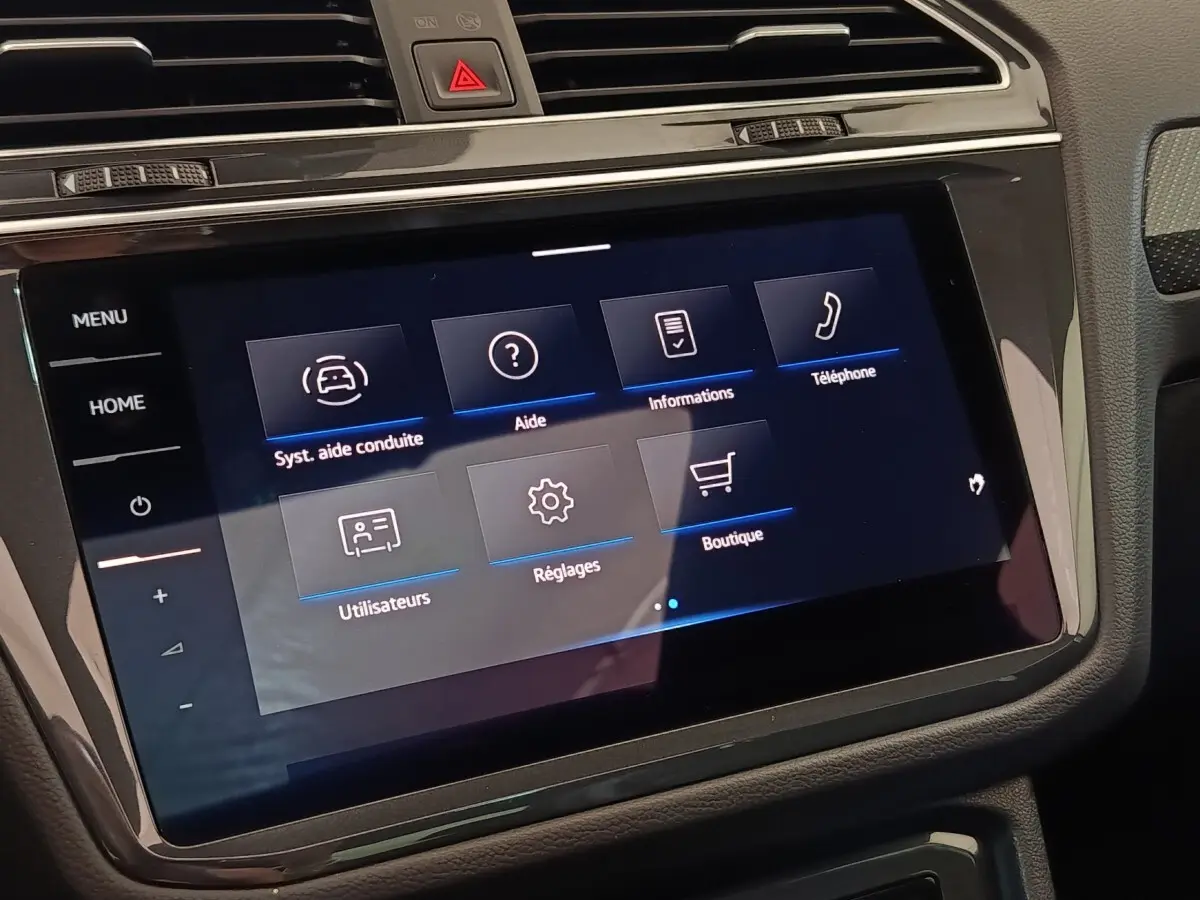 Écran tactile central du tableau de bord du Volkswagen Tiguan blanc, affichant le menu des aides à la conduite.