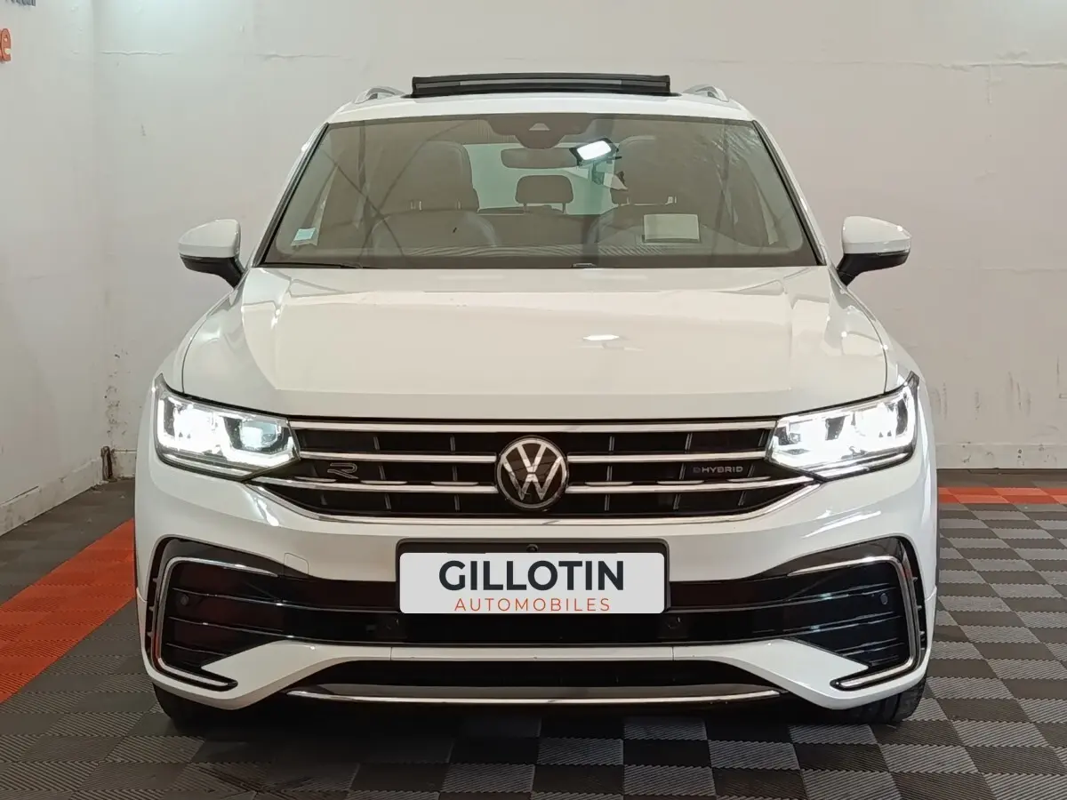 Volkswagen Tiguan 1.4 eHybrid blanc vu de face, phares LED allumés et calandre R-Line distinctive.