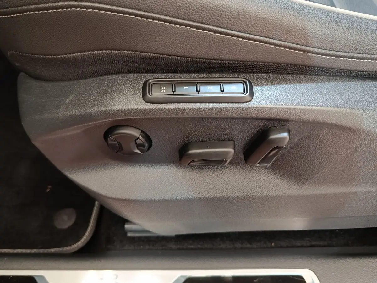 Réglages électriques des sièges côté conducteur du Volkswagen Tiguan blanc, avec boutons de mémoire de position.