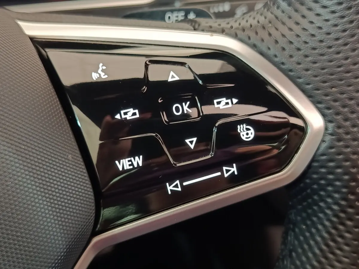 Gros plan sur les commandes multifonctions noires du volant cuir du Volkswagen Tiguan blanc 2023 hybride rechargeable.