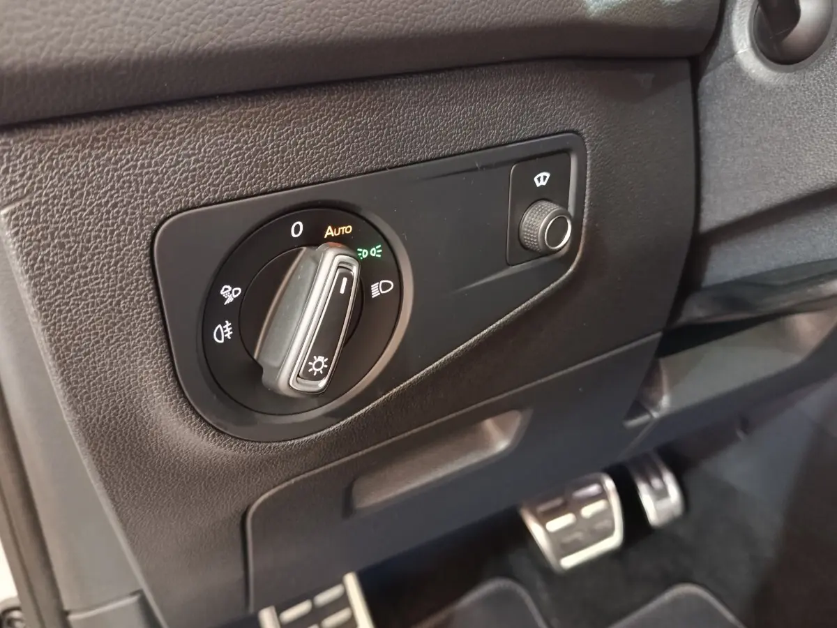 Détail du tableau de bord côté gauche du Volkswagen Tiguan blanc 2023, avec commande des phares et réglage du lave-glace.