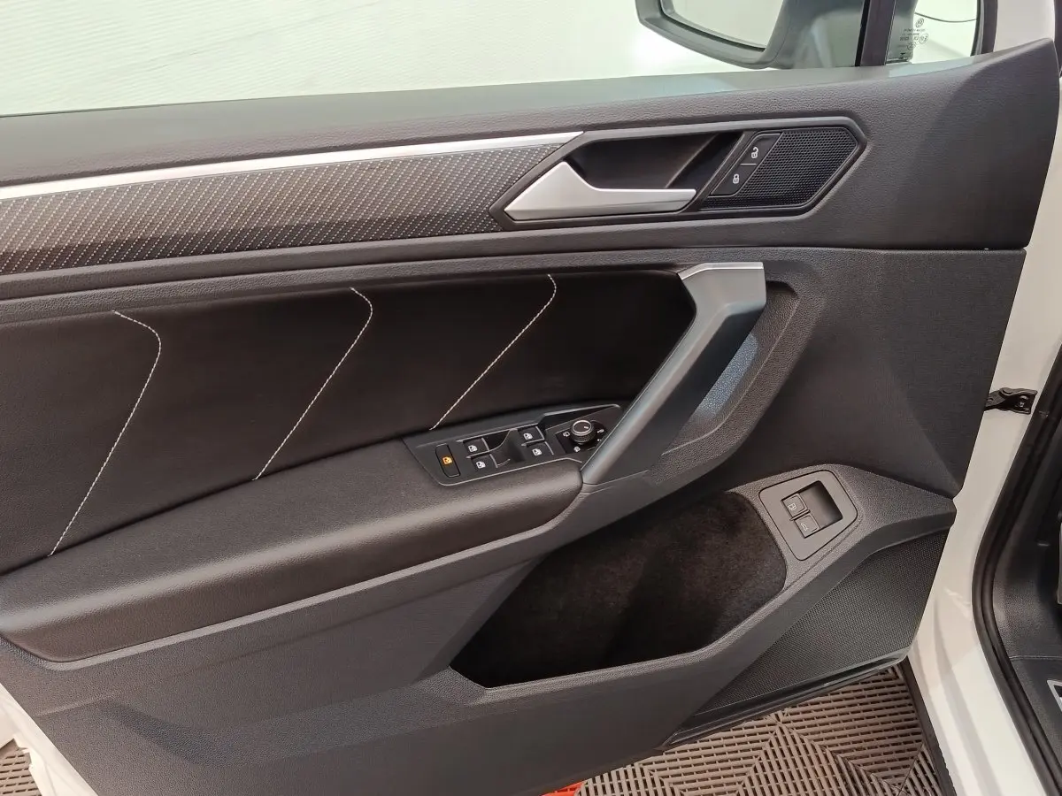 Vue intérieure côté gauche de la porte avant blanche du Volkswagen Tiguan 1.4 eHybrid avec garniture noire et surpiqûres blanches.