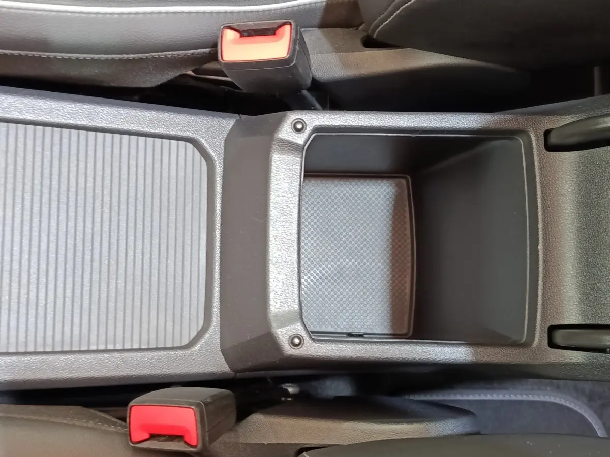 Vue plongeante sur le rangement central noir entre les sièges avant du Volkswagen Tiguan blanc 2023 hybride rechargeable.