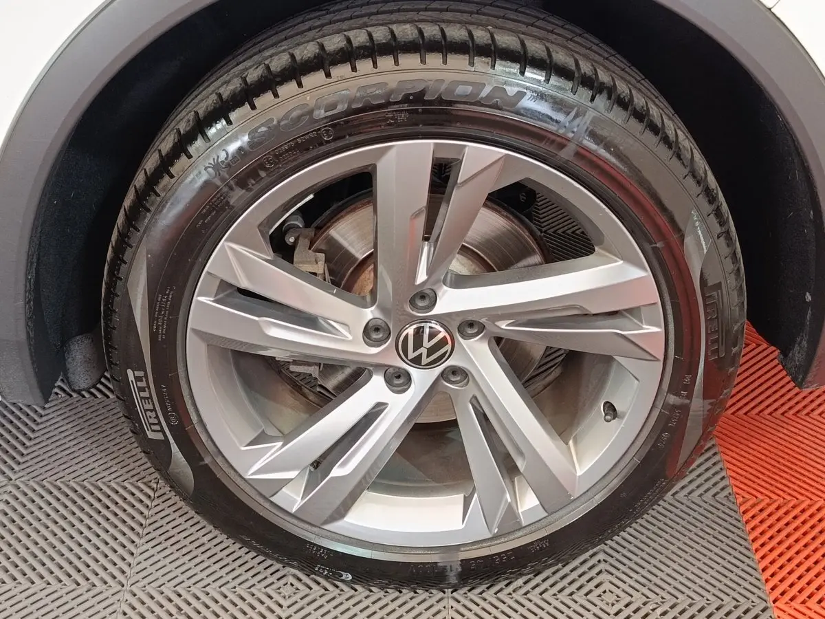 Gros plan sur la roue avant droite du Volkswagen Tiguan blanc, jante alliage 5 branches doubles et pneu Pirelli Scorpion.