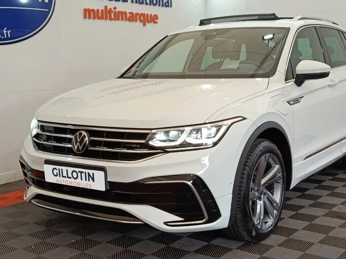 Vue 3/4 avant d'un Volkswagen Tiguan blanc hybride rechargeable avec calandre R-Line et jantes alliage grises.