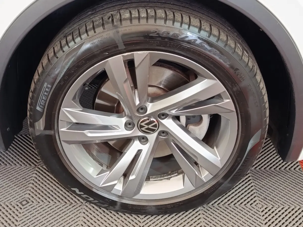 Gros plan sur la roue avant gauche avec jante alliage argentée et pneu Pirelli sur Volkswagen Tiguan blanc.