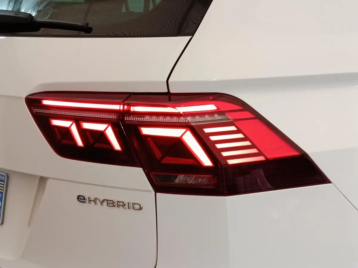 Gros plan sur le feu arrière droit allumé d’un Volkswagen Tiguan blanc eHybrid 2023, avec logo eHYBRID visible.