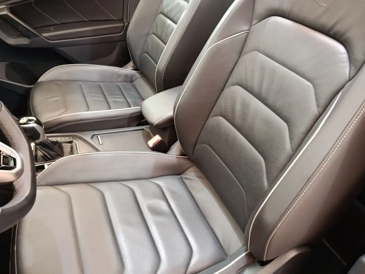 Gros plan sur les sièges avant en cuir noir du Volkswagen Tiguan 1.4 eHybrid 2023, vue côté conducteur.