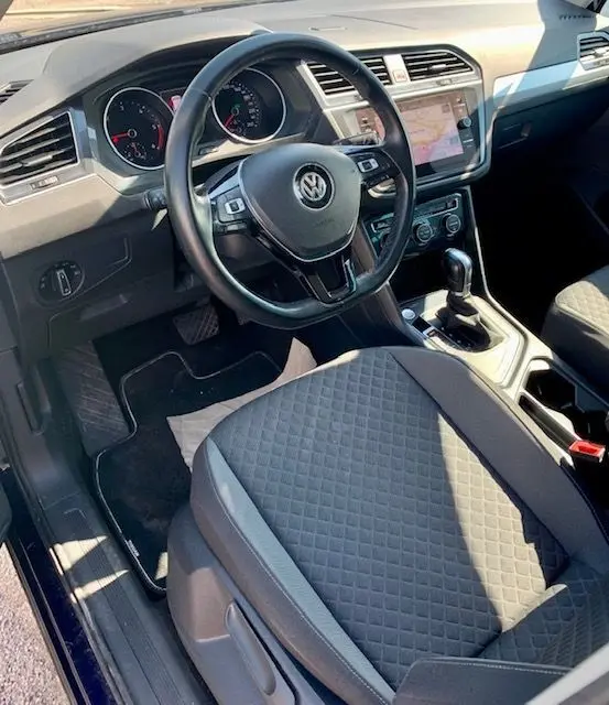 Intérieur du Volkswagen Tiguan 2018, vue côté conducteur montrant volant, tableau de bord et siège tissu gris.