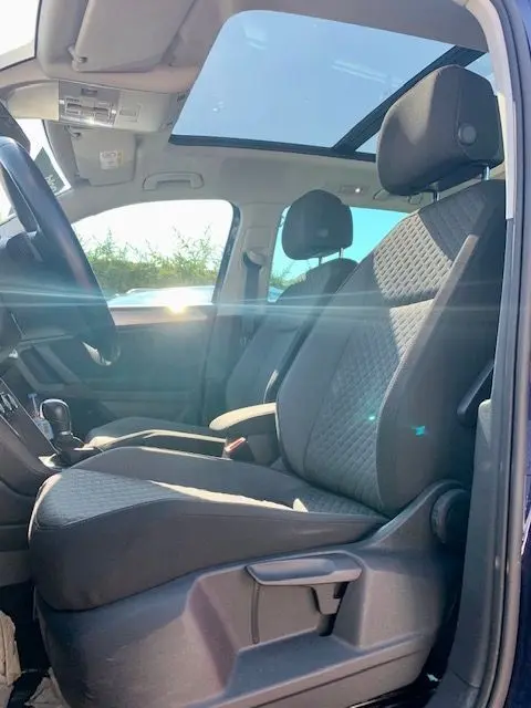 Intérieur du Volkswagen Tiguan 2018 bleu, vue côté gauche sur les sièges avant et toit panoramique lumineux.