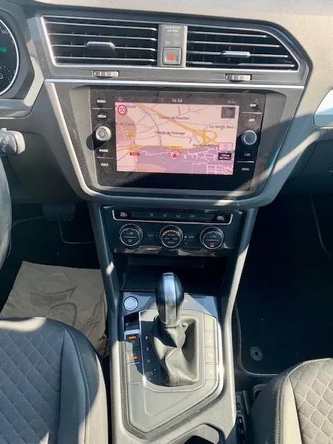 Vue intérieure centrée sur la console centrale du Volkswagen Tiguan 2018 bleu, avec écran tactile et levier de boîte auto DSG7.