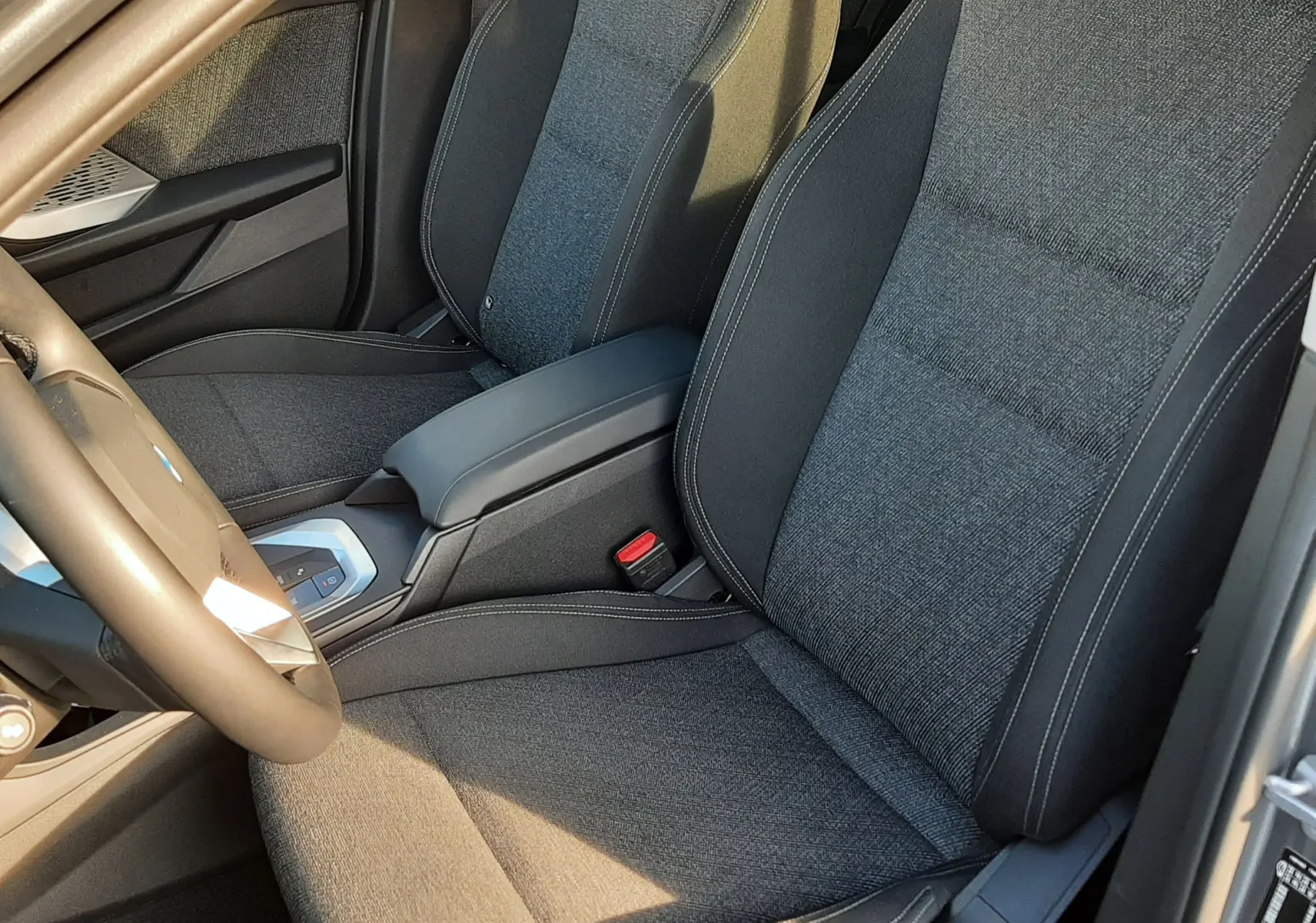 Vue intérieure rapprochée des sièges avant en tissu gris foncé de la BMW Série 1 F70 120D M Sport Design 2025.