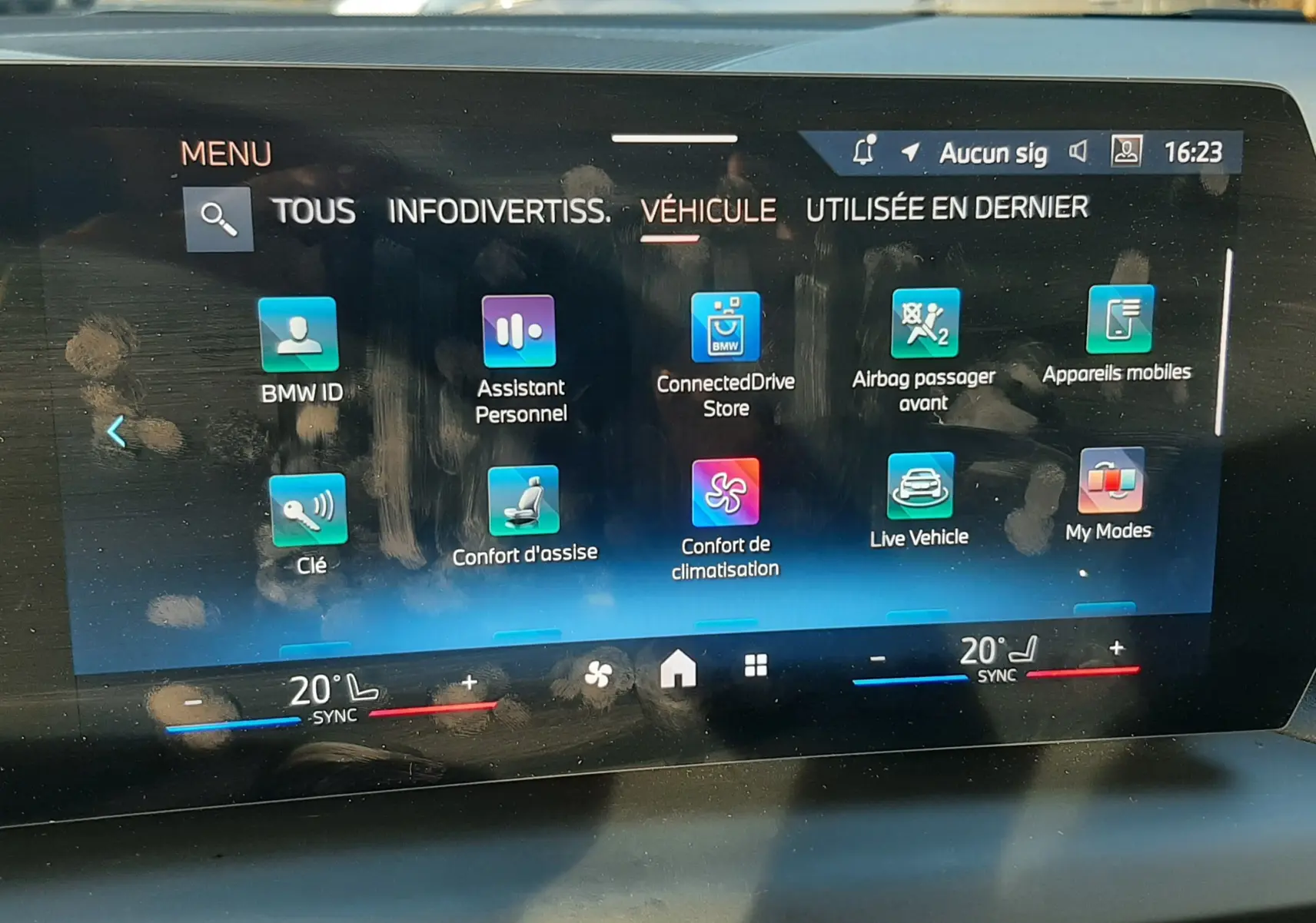 Écran tactile central de la BMW Série 1 2025 affichant les options de confort et connectivité, intérieur noir visible.