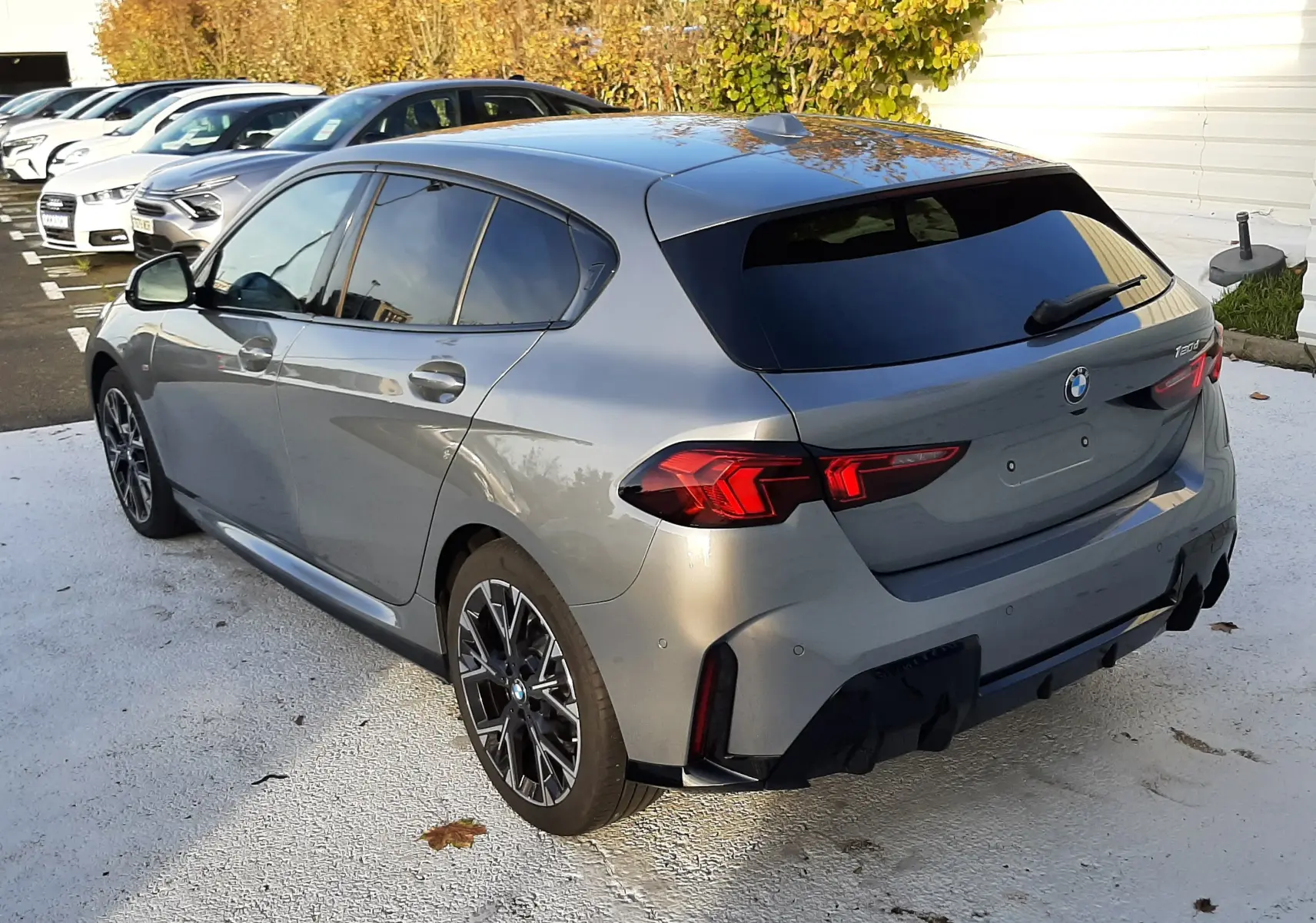 BMW Série 1 120d M Sport gris Skyscraper vue 3/4 arrière droit, jantes 18'' bicolores et vitres teintées.