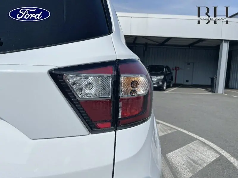 Gros plan sur le feu arrière droit du Ford Kuga blanc glacier, mettant en valeur le hayon motorisé et les lignes nettes du coffre.