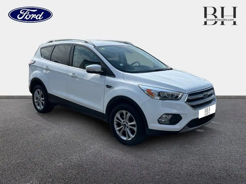 Ford Kuga blanc glacier en 3/4 avant droit avec barres de toit aluminium et jantes alliage.