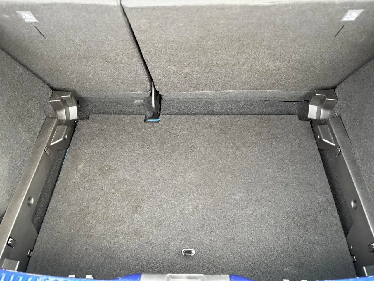 Coffre ouvert vu de dessus de la Dacia Sandero Stepway Bleu Iron, montrant l'espace de chargement vide et les dossiers arrière rabattus.