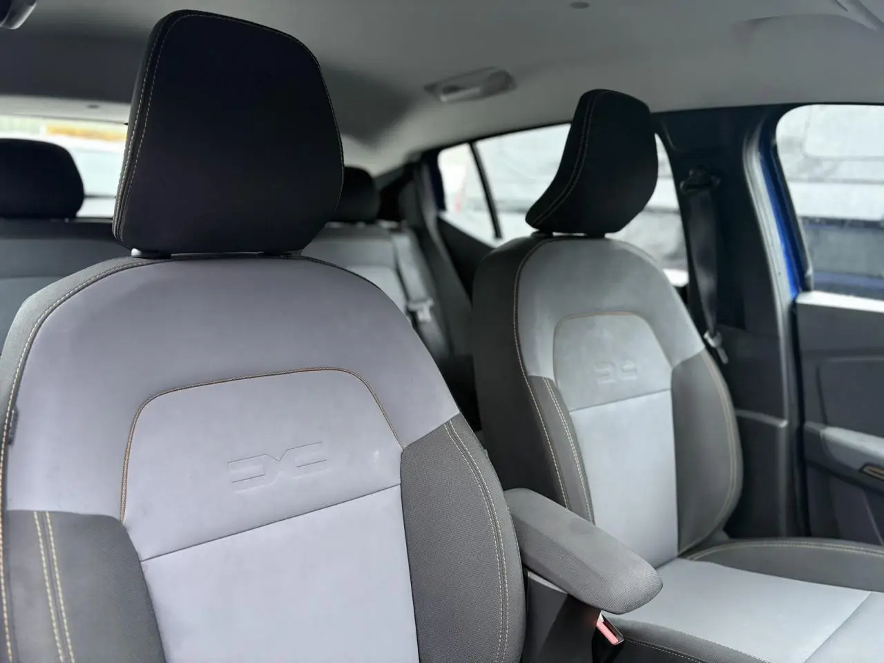 Vue intérieure des sièges avant en sellerie TEP MicroCloud gris avec surpiqûres contrastantes dans une Dacia Sandero Stepway Bleu Iron.