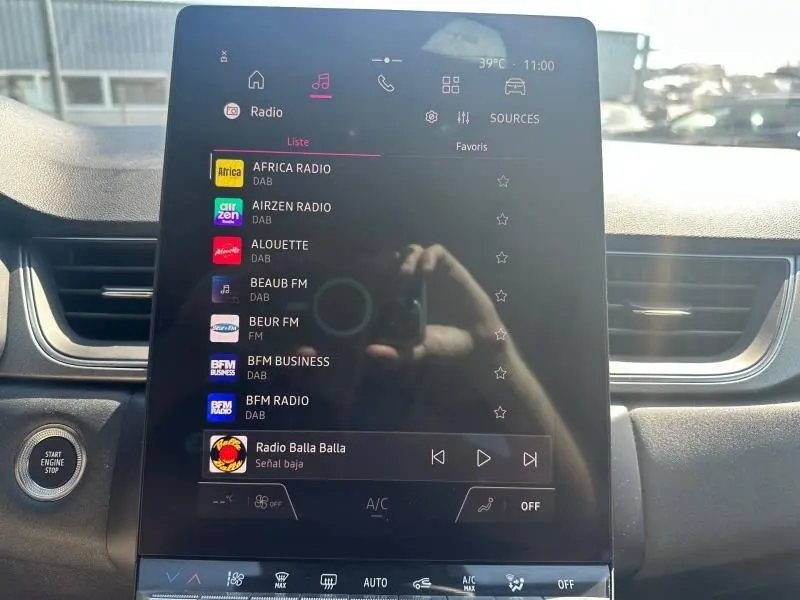 Vue intérieure du tableau de bord du Renault Captur 2025 avec écran tactile central affichant les stations radio, bouton start/stop visible à gauche.