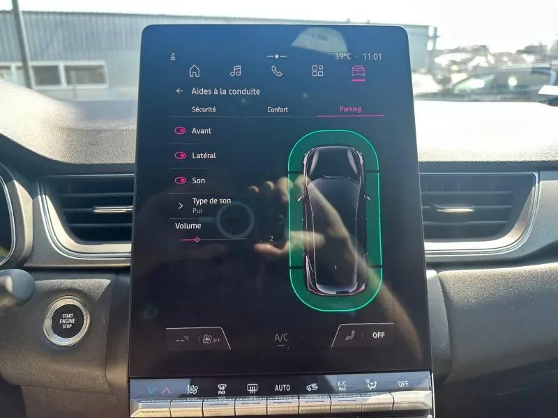 Écran tactile intérieur du Renault Captur 2025 affichant l'aide au stationnement et les réglages audio.