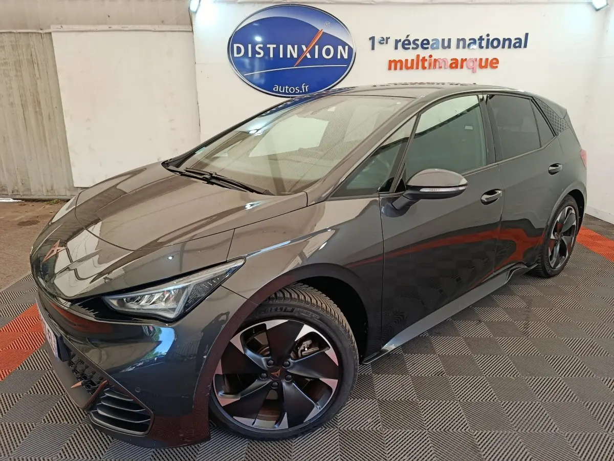 Vue 3/4 avant droit d'une CUPRA BORN gris foncé avec jantes noires et logo distinctif sur calandre.