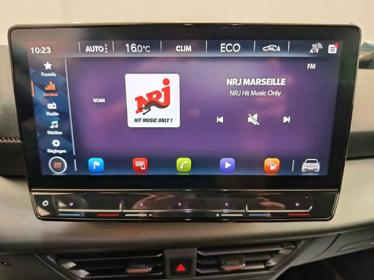 Écran tactile central affichant la radio NRJ dans l'habitacle d'une CUPRA BORN gris foncé, vue de face.