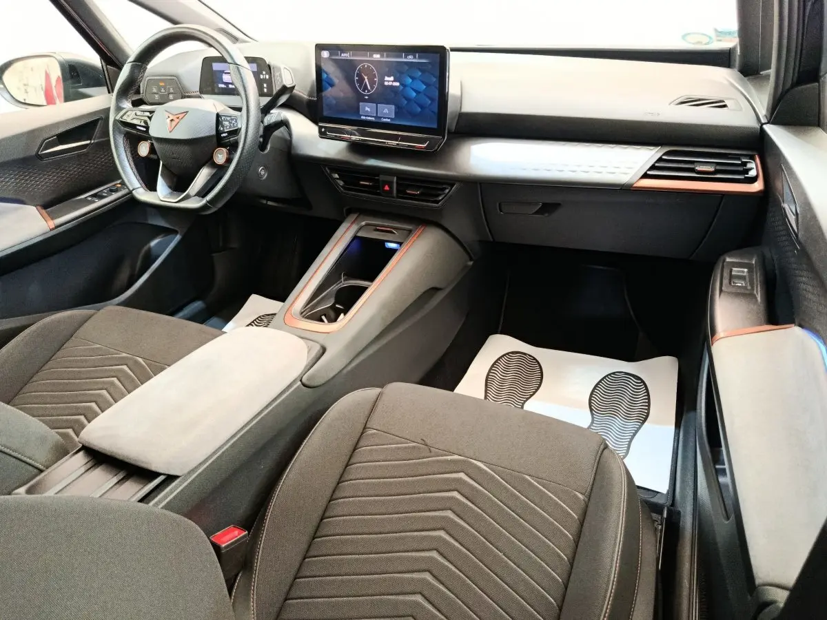 Intérieur du CUPRA BORN 230ch vu côté passager, avec tableau de bord noir et gris clair, volant cuir et écran tactile central.