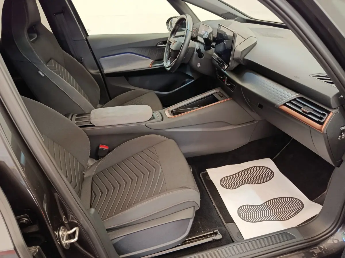 Intérieur avant droit de la CUPRA BORN gris foncé 2023, avec tableau de bord moderne et sièges en tissu noirs.