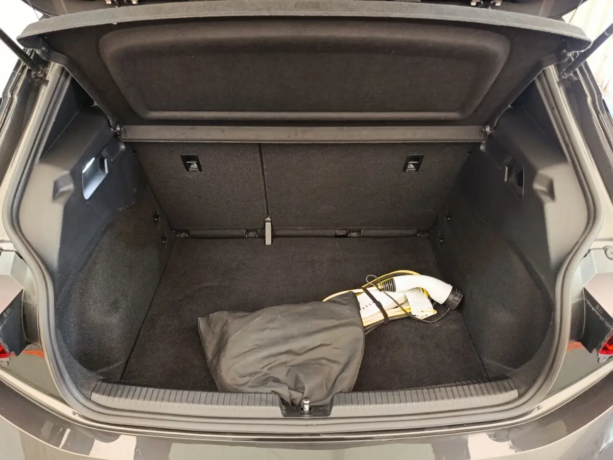 Coffre ouvert d'une CUPRA Born gris foncé, vue arrière, avec câble de charge électrique visible à l'intérieur.