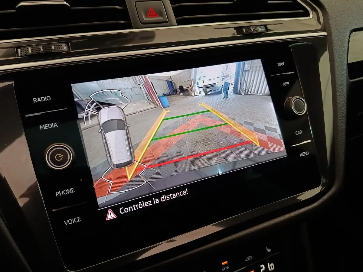 Écran tactile intérieur du Volkswagen Tiguan 2021 montrant l’aide au stationnement avec caméra de recul et guidage coloré.