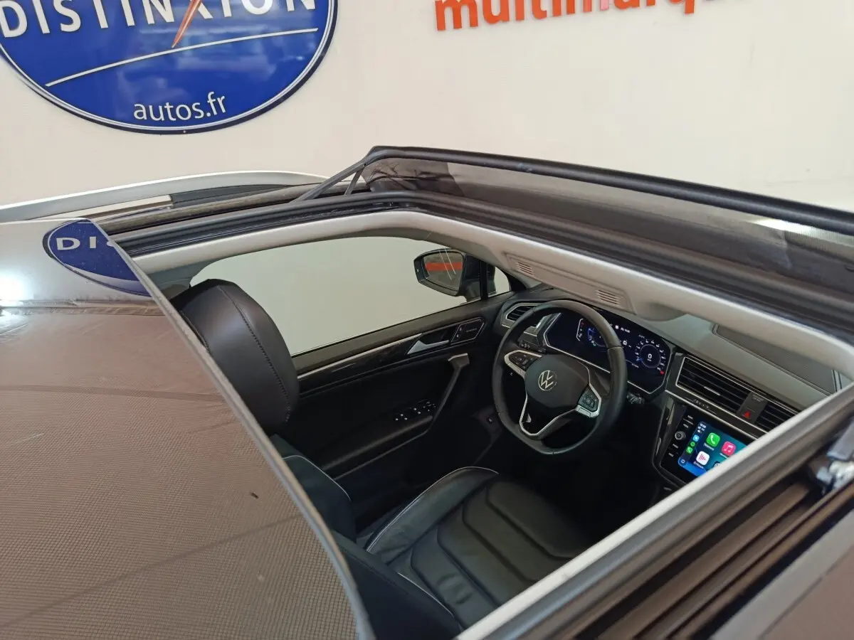 Vue intérieure côté conducteur du Volkswagen Tiguan noir 2021, volant cuir multifonctions et écran tactile visible.