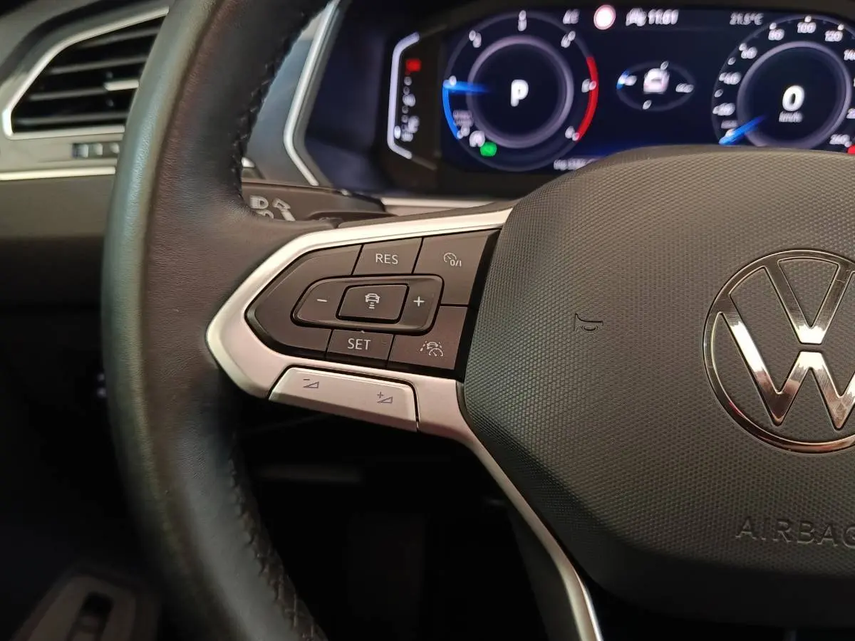 Gros plan sur le volant cuir noir du Volkswagen Tiguan 2021, avec commandes multifonctions et tableau de bord digital.