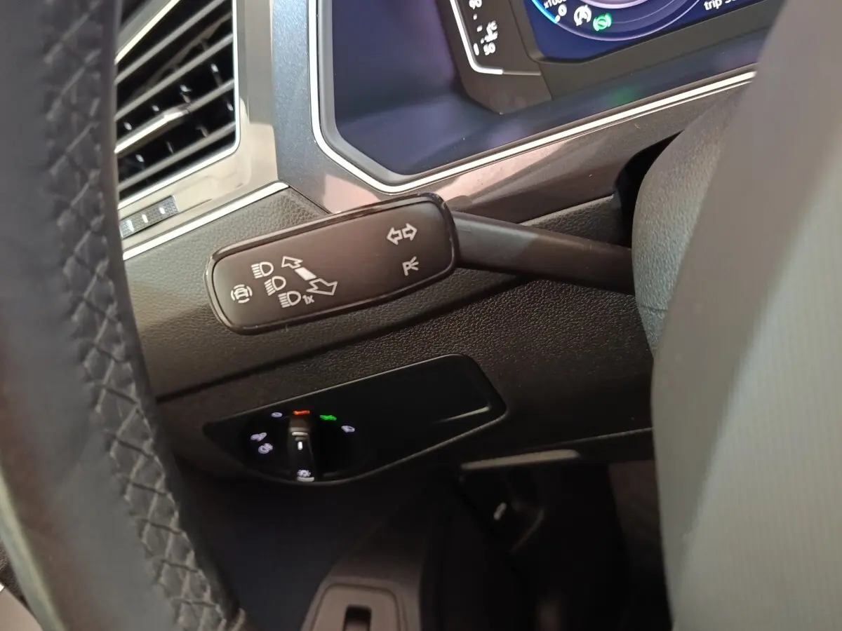 Gros plan sur la manette de clignotants et le tableau de bord numérique du Volkswagen Tiguan noir, intérieur conducteur.