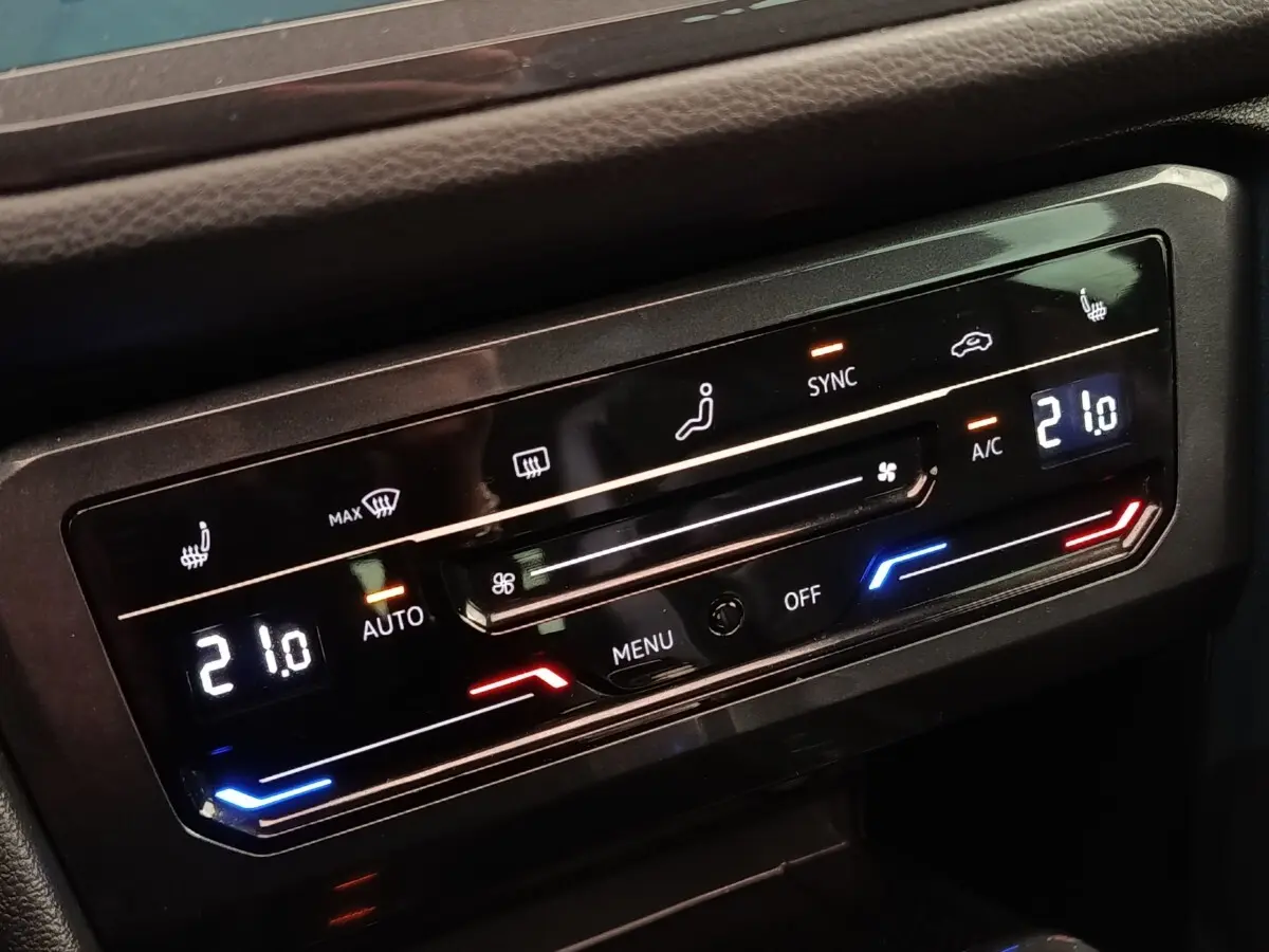Détail du panneau de commande de la climatisation automatique 3 zones du Volkswagen Tiguan noir, affichage digital à 21°C.