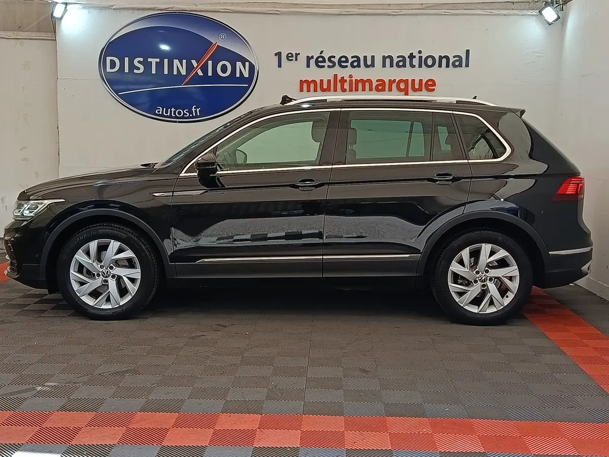 Vue de profil côté gauche d'un Volkswagen Tiguan noir 2.0 TDI 150 DSG7 Elegance dans un showroom.