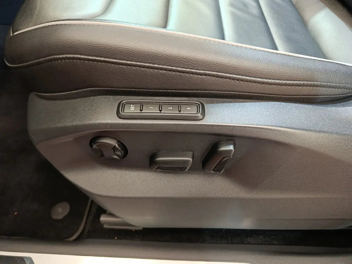 Détail côté gauche du siège conducteur noir en cuir avec commandes électriques et mémoire sur Volkswagen Tiguan 2021.