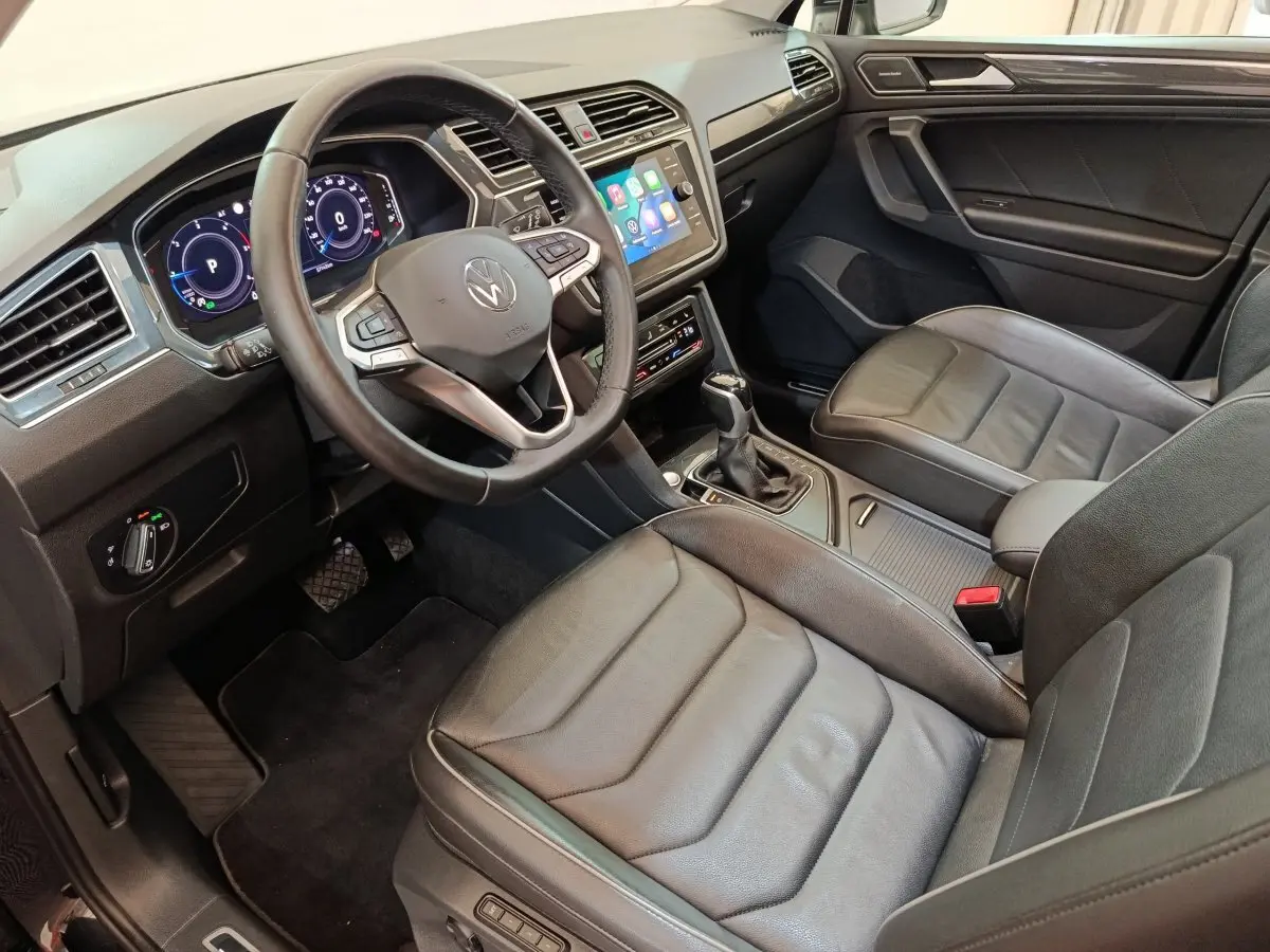 Vue intérieure côté conducteur du Volkswagen Tiguan 2.0 TDI noir, volant cuir multifonctions et écran tactile central.