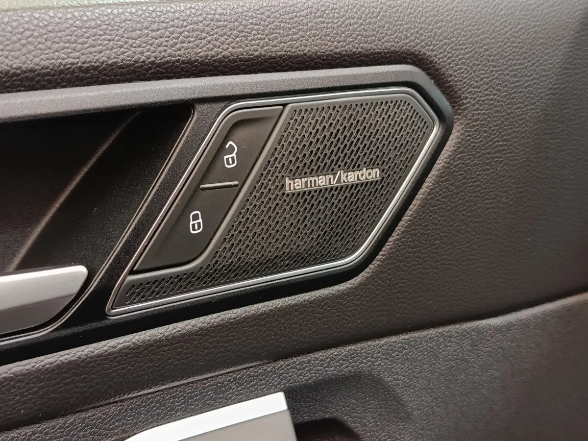 Détail intérieur montrant l'enceinte Harman Kardon et les boutons de verrouillage sur la porte noire du Volkswagen Tiguan.