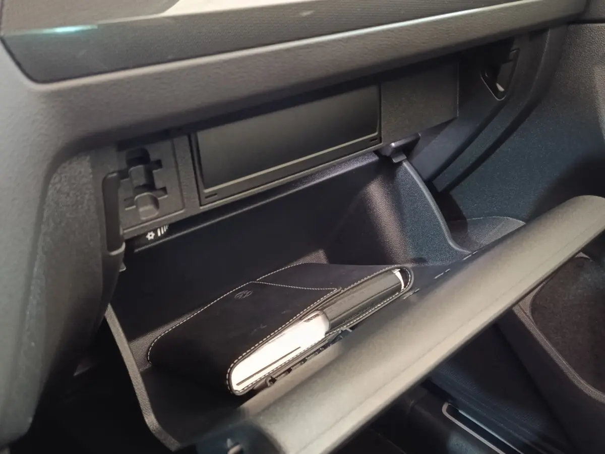 Vue rapprochée de la boîte à gants ouverte du Volkswagen Tiguan 2021, avec un carnet noir à l'intérieur.