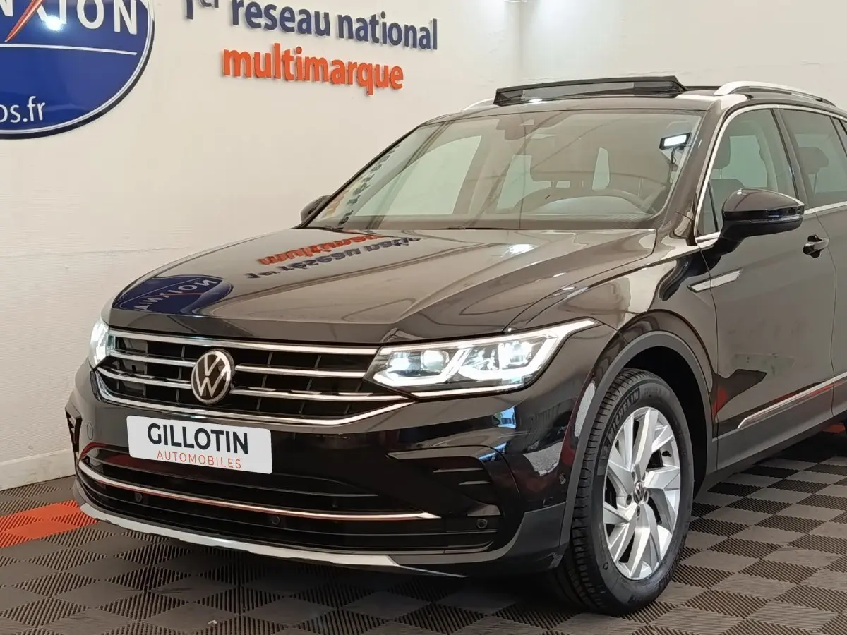 Volkswagen Tiguan noir 2021 en 3/4 avant droit, avec phares LED allumés et jantes alliage visibles.