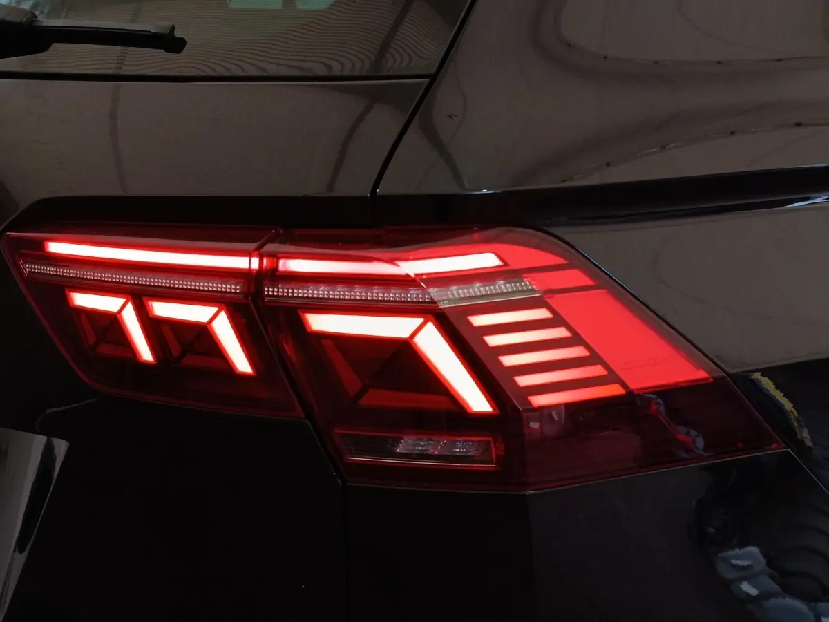 Gros plan sur le feu arrière droit rouge allumé du Volkswagen Tiguan noir, soulignant ses lignes LED distinctives.