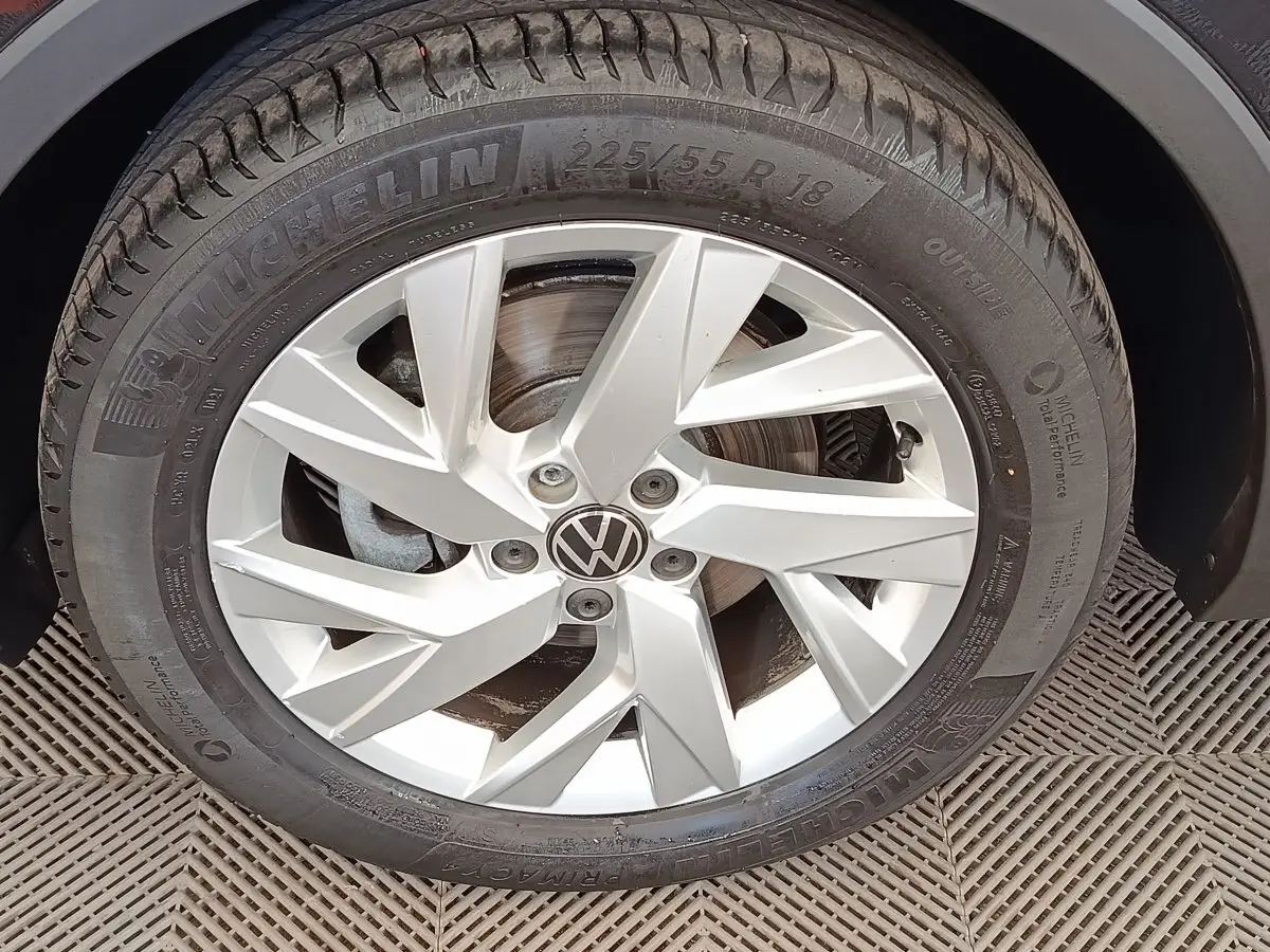 Gros plan sur la roue avant droite du Volkswagen Tiguan noir, jante alliage argentée avec logo VW central.