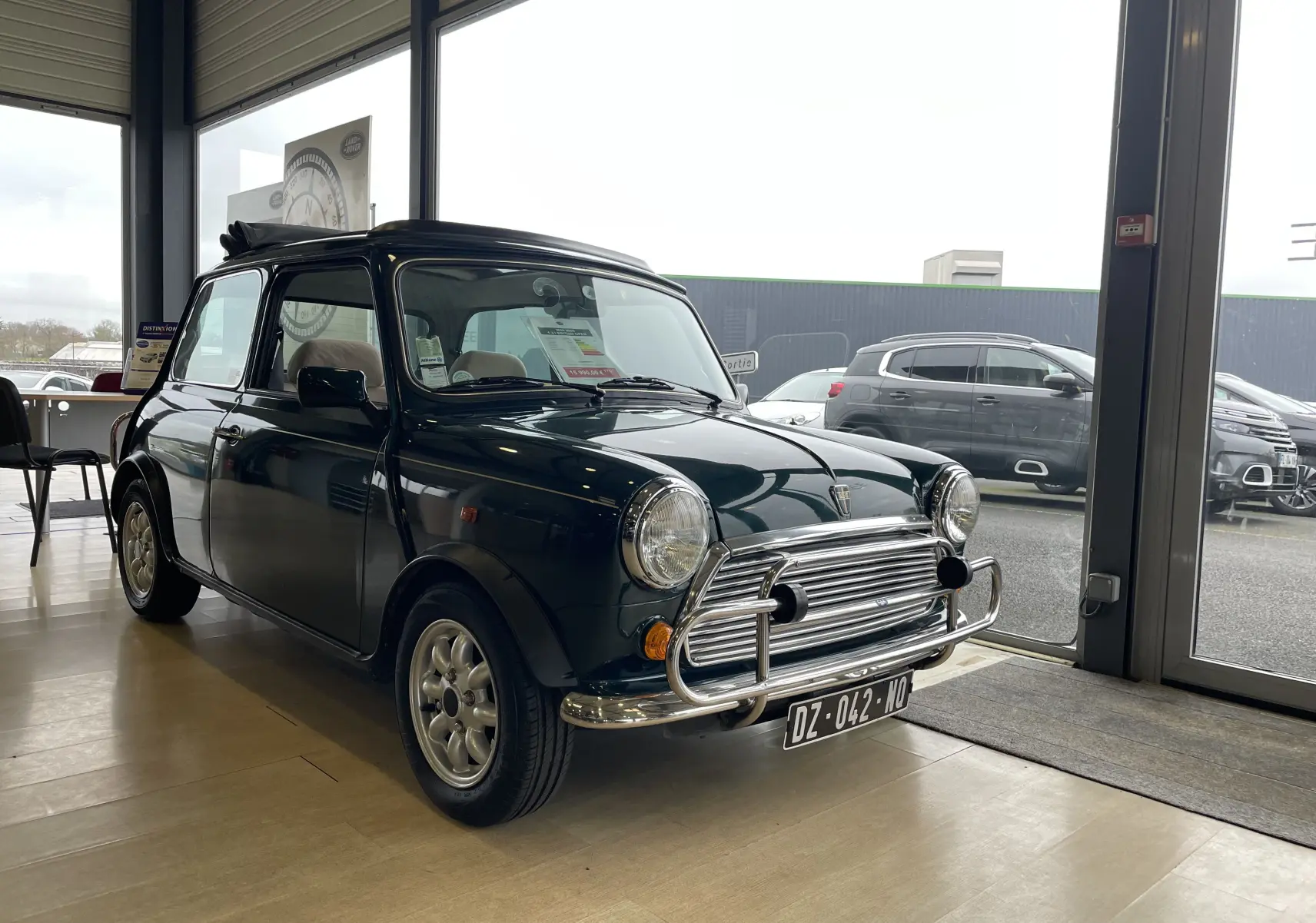 Vue 3/4 avant gauche d'une MINI 1.3 i British Open 1995 en British Racing Green avec pare-chocs chromé intérieur showroom.
