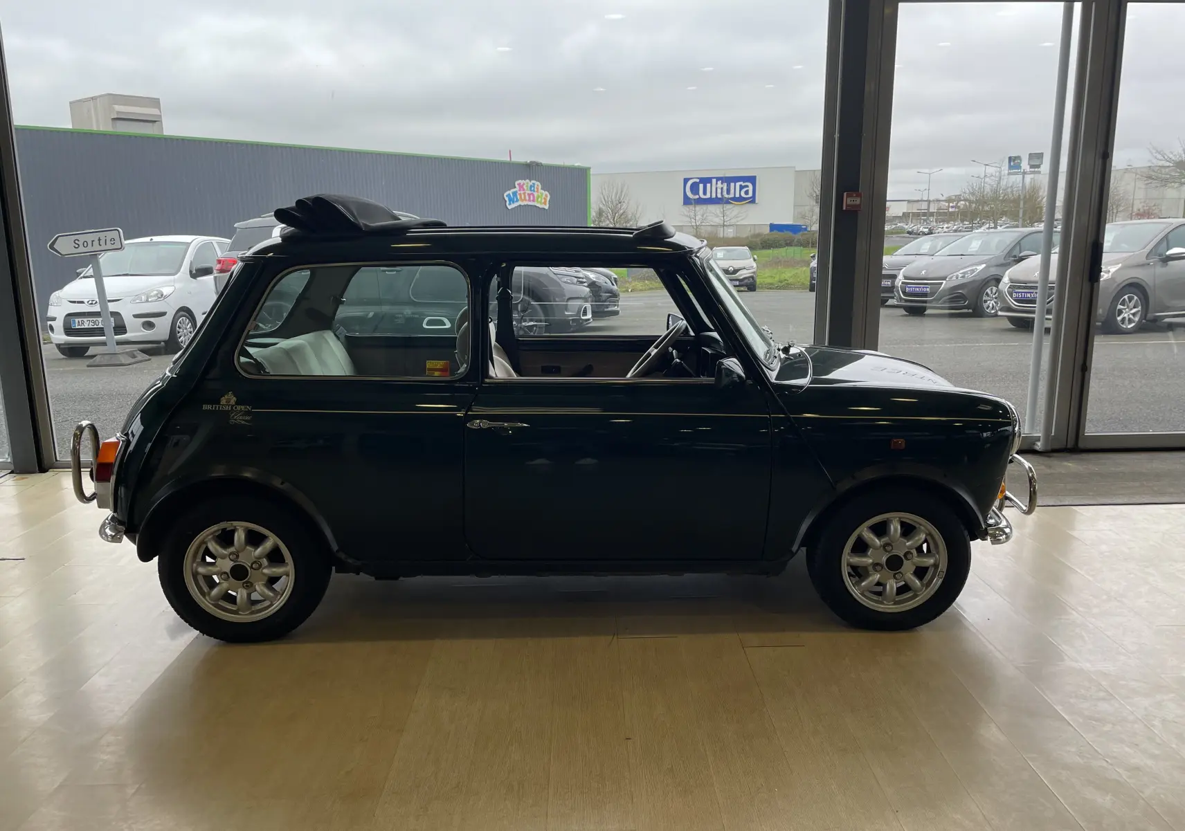 Profil côté gauche d'une MINI 1.3 i BRITISH OPEN 1995 en British Racing Green avec toit ouvrant partiellement ouvert.
