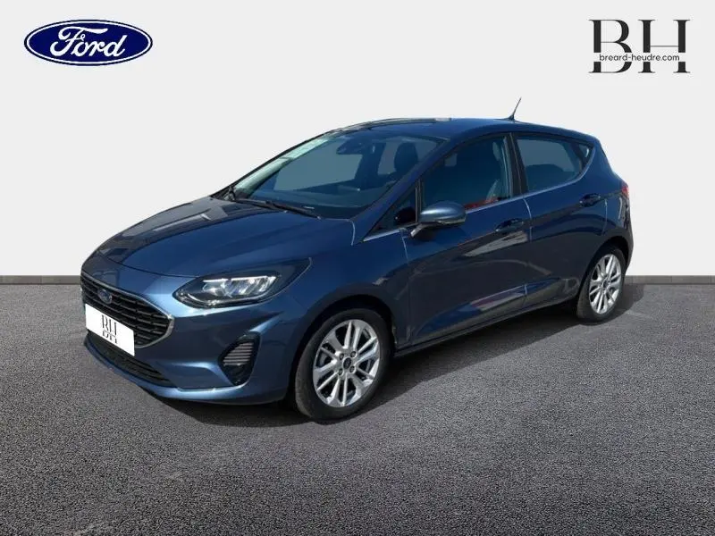 Ford Fiesta 2022 bleu azur métallisé vue 3/4 avant droit avec calandre chromée et jantes alu 16 pouces.