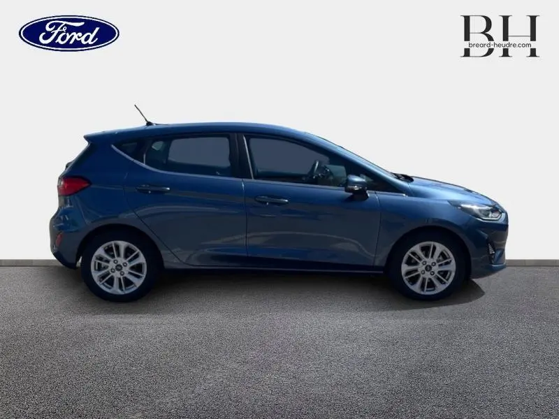 Profil droit d'une Ford Fiesta 1.0 EcoBoost Hybrid 125ch Titanium Business 2022 en bleu azur métallisé avec jantes alu 16 pouces.