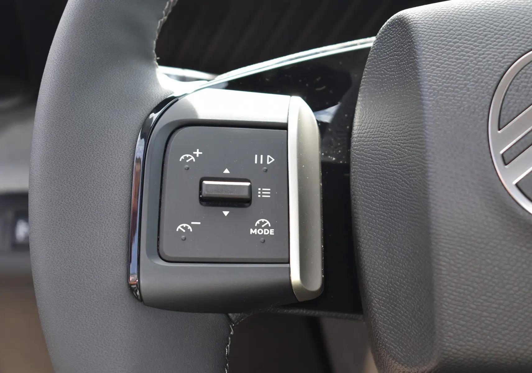 Gros plan sur les commandes à gauche du volant du Citroën C3 2025 bleu toit noir, avec régulateur de vitesse et mode.