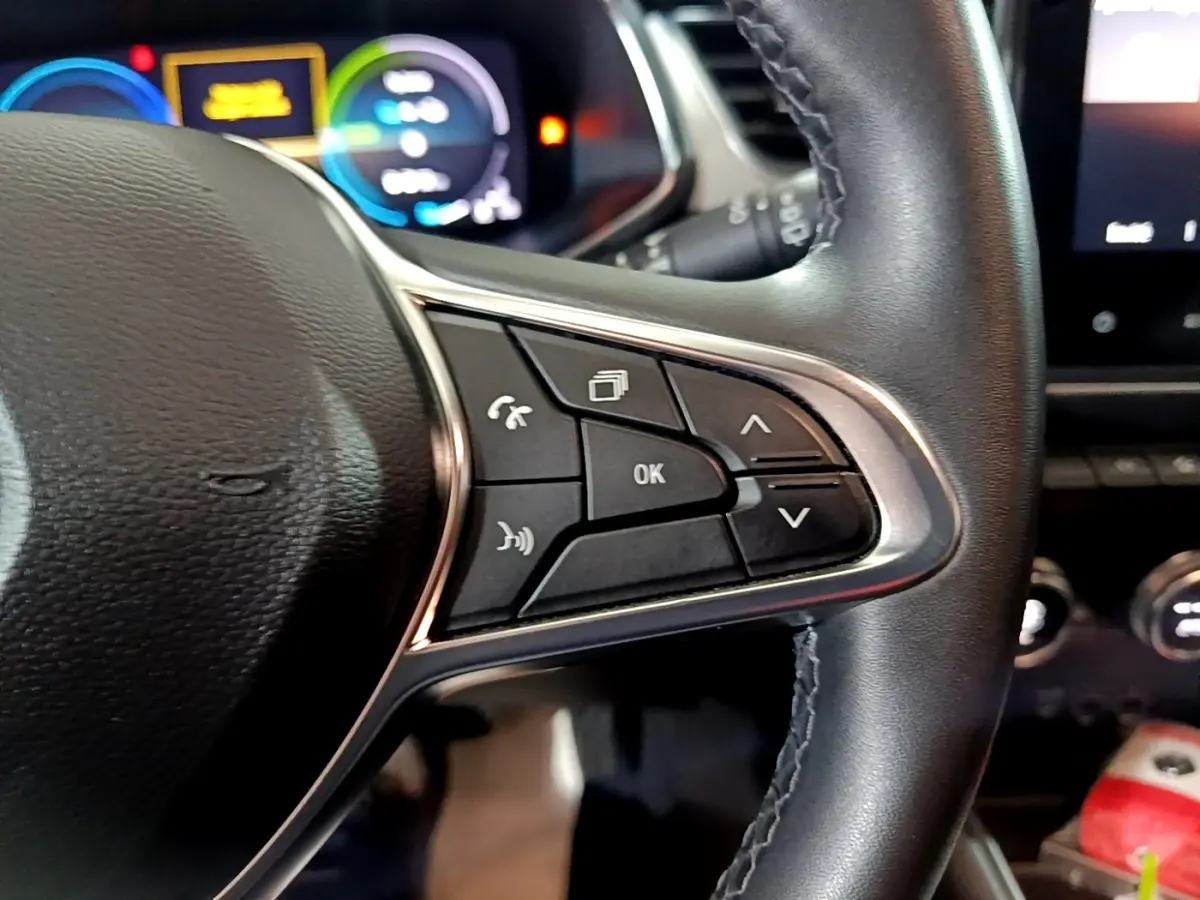 Gros plan sur le volant cuir noir du Renault Captur Intens E-Tech 2021, avec commandes multifonctions et tableau de bord numérique flou.