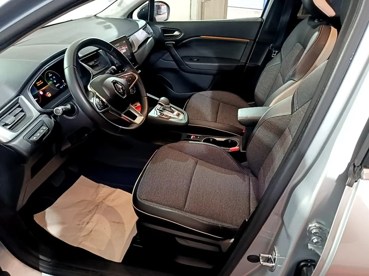 Intérieur côté conducteur du Renault Captur gris clair 2021, montrant sièges tissu et tableau de bord avec écran tactile.